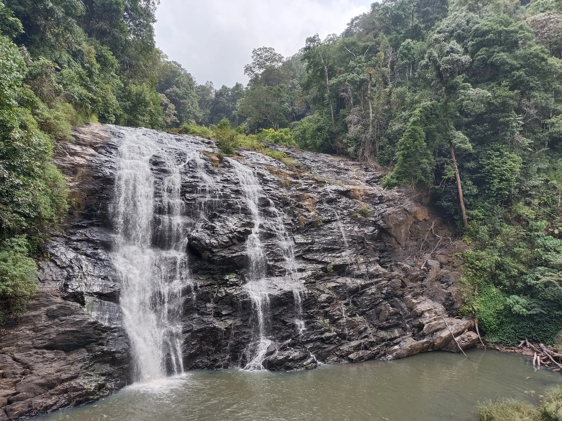 Abbey Falls cascading over dark rock amid dense forest in Coorg